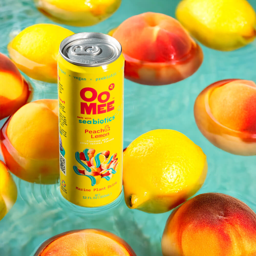 OoMee Peach & Lemon Marine Plant Drink with Seabiotics™ - 12 oz Can Surrounded by Fresh Peaches and Lemons Floating in Vibrant Water. Vegan, Prebiotic, Low-Sugar Ready-to-Drink Beverage for Gut Health and Craving Control.