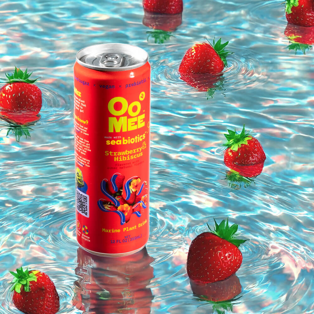 OoMee Strawberry & Hibiscus Marine Plant Drink with Seabiotics™ - 12 oz Can Surrounded by Fresh Strawberries Floating in Vibrant Water. Vegan, Prebiotic, Low-Sugar Ready-to-Drink Beverage for Gut Health and Cravings Control.