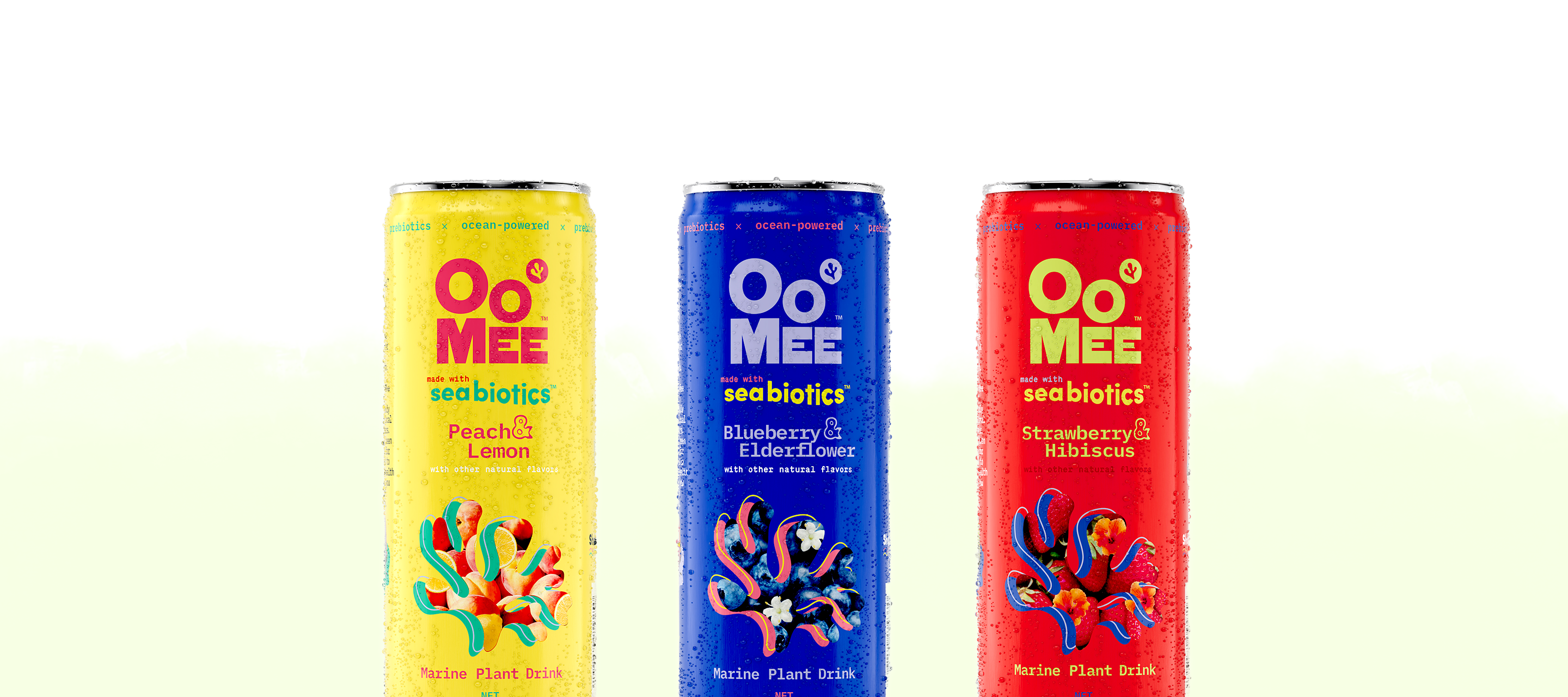 Three colorful OoMee marine plant drink cans—Peach & Lemon (yellow), Blueberry & Elderflower (blue), and Strawberry & Hibiscus (red)—standing upright with water droplets against a soft white and pale green background.