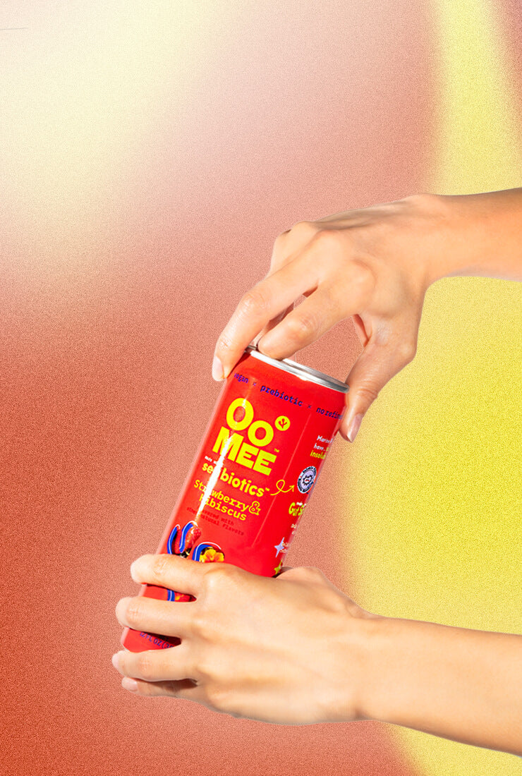 Hands Opening OoMee Strawberry & Hibiscus Flavor Beverage Can Against Red and Yellow Gradient Background - Marine-Based, Vegan, Prebiotic Drink for Gut Health.f